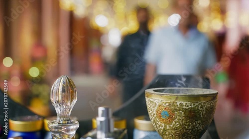 Close up of crystal perfume bottle stopper, ornate golden decorative bowl, luxury fragrance display at upscale gathering with blurred festive lights background.