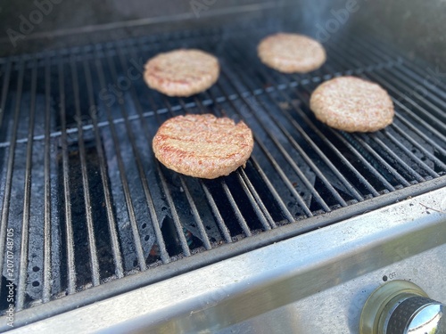 Fotografie Rohe Burger-Patties auf einem heißen Grillrost vor dem Grillen