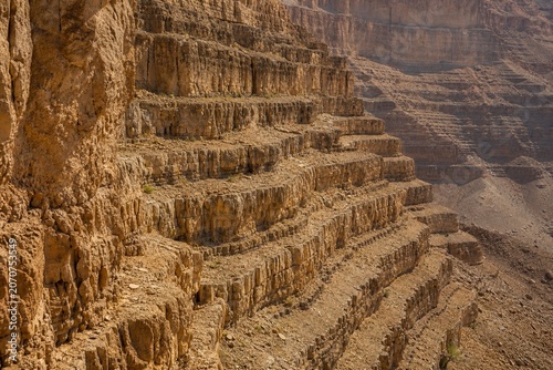 Stepped rock layers in a canyon wall, desert landscape.