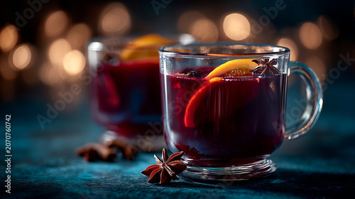 Glass of hot aromatic mulled wine with cinnamon sticks and orange slice on wooden