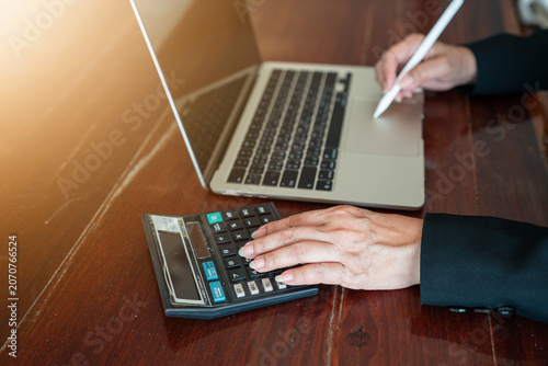 Businessman holding stylus pen using laptop and calculator for financial analysis.