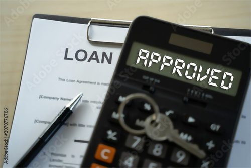 Financial success concept with a loan agreement document, a calculator showing 'APPROVED', and a house key, representing mortgage approval and home ownership