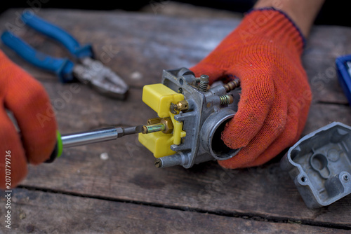 Photos Mechanic unscrews the jets of the carburetor for cleaning