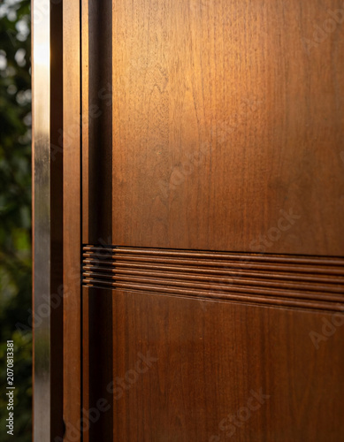 Close-up of a wooden door with decorative lines and metal frame outdoors
