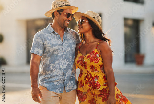 Happy couple in summer clothes walking together on a sunny day outdoors