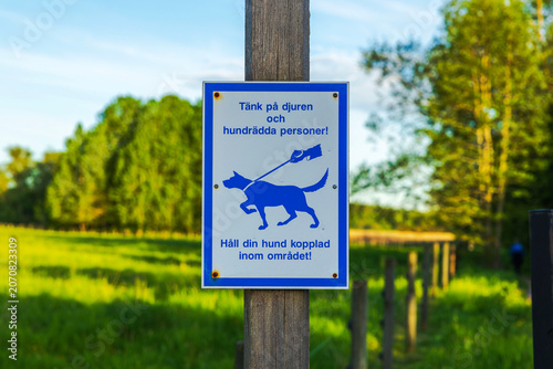 Close-up view of pet safety sign reminding dog owners to keep animals on leash in park landscape. Sweden. Uppsala. 
