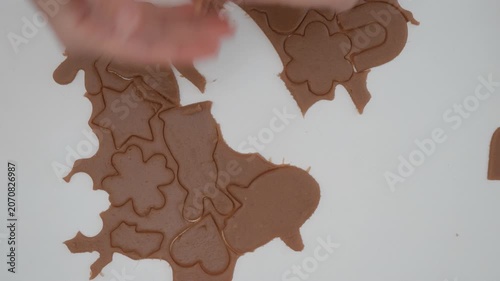 Woman hands remove excess pastry dough separating shaped gingerbread cookies on table. Female chef lifts raw biscuit forms for holiday baking recipe domestic lifestyle food production process.