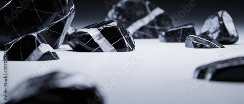 Polished black stones with white veins arranged on a smooth surface