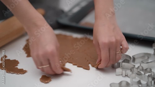 Woman hands transfer raw gingerbread cookie shapes onto baking sheet. Female chef prepares homemade chocolate dessert pastry for holiday confectionery recipe process in a domestic kitchen.