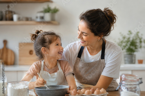 mother, daughter, kitchen, cooking, meal, smiles, bonding, ingredients, bowl, mixing, family, activity, preparation, time, home, shelf, plants, fun, joy, eggs, milk, flour, recipe, playful, warmth, to