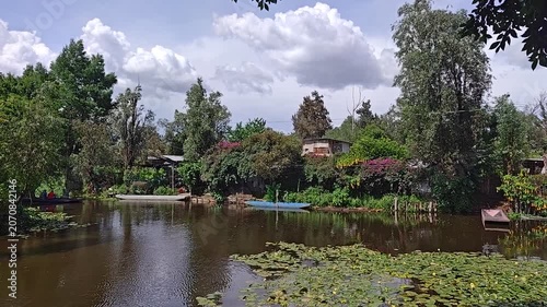 Tranquil Xochimilco Canal with Traditional Boats Docked Among Lush Greenery, Mexico City