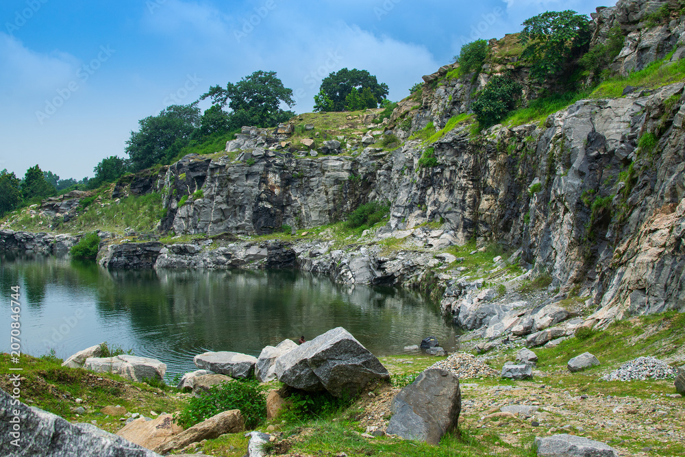 Fototapeta premium Rocks and stones of Tarpania Lake, Marble Lake, Blue Dam, Patal Dam or Durga Bera,a scenic lake in the Ajodhya Hills of Purulia, West Bengal, India. Blue water surrounded by marble-like rocky cliffs.