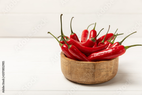 Chili pepper and chili powder on a wooden table. Red hot natural chili pepper. Organic fresh chili pepper flakes and paprika powder in a bowl on the table. Spicy spices. Copy space. Space for text.