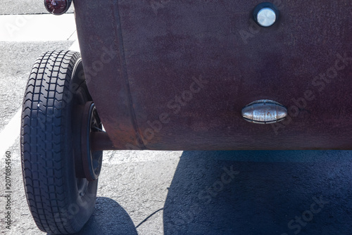 Fotografie Weathered vintage car rear panel with rusted patina, exposed wheel, metal fixtur