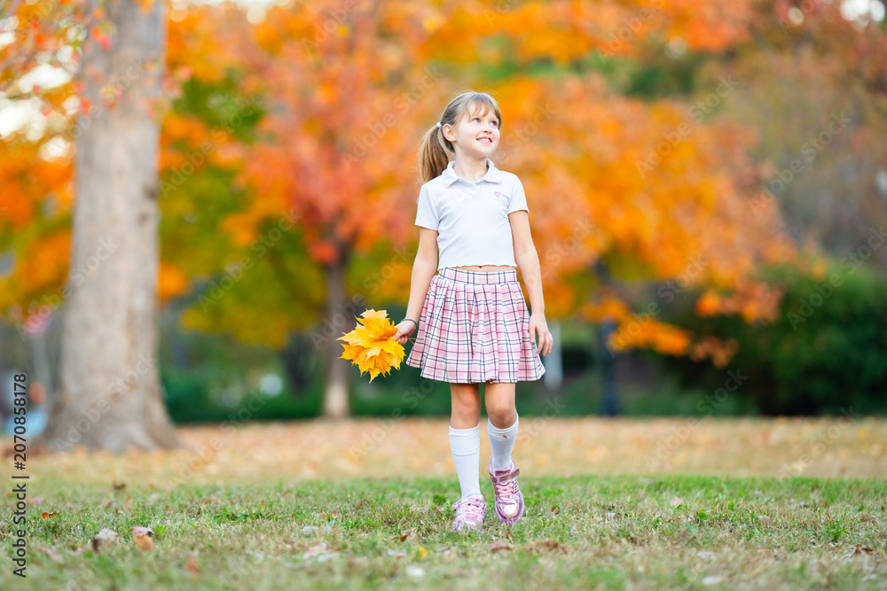Fototapeta premium Leaves in girl hand. Leaves match autumn foliage. Yellow leaves in child portrait. Maple leaves outdoors in park.