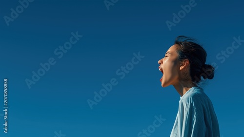 Person Yawning Against Clear Blue Sky