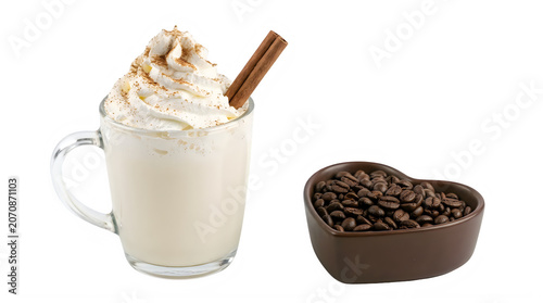 Glass mug of creamy coffee drink with whipped cream and cinnamon sticks next to heart shaped bowl of coffee beans transparent background