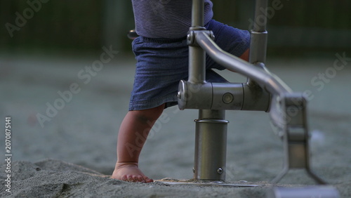 Obraz na plátně Toddler stepping into sandbox walking with unstable steps then stumbling falling