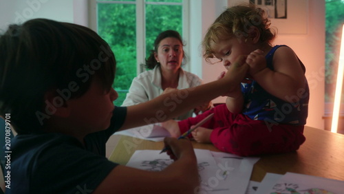 Fotografie Toddler grabbing pen from sibling while sitting on table interrupting drawing ac