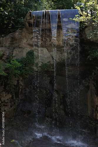 Waterfall Flowing Through Rocky Landscape and Greenery