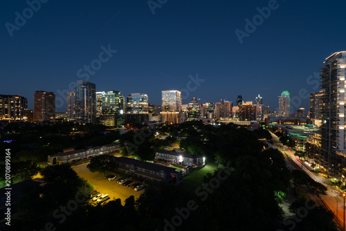 Night time view of the skyscrapers and office buildings in downtown Dallas, Texas glowing just afer sunset as seen from the roof of a building.