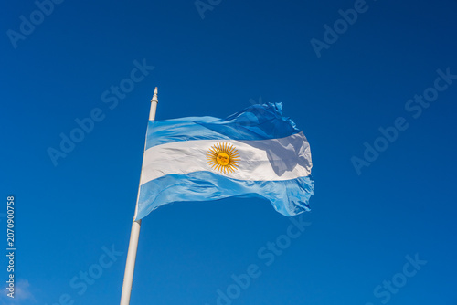 National flag of Argentina waving on a flagpole against a clear blue sky