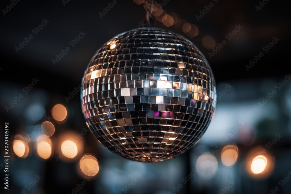 Obraz premium Studio shot of a metallic disco ball suspended in moody lighting with colorful light patterns