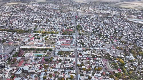 Aerial drone shot of the beautiful city of Gyumri in Armenia, showcasing its historic architecture, busy city squares, streets, and the famous landmark Holy Saviour's Church during autumn.

