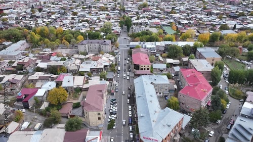 Aerial drone shot of the beautiful city of Gyumri in Armenia, showcasing its historic architecture, busy city squares, streets, and the famous landmark Holy Saviour's Church during autumn.

