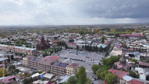 Aerial drone shot of the beautiful city of Gyumri in Armenia, showcasing its historic architecture, busy city squares, streets, and the famous landmark Holy Saviour's Church during autumn.

