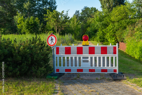 Photos Barrier blocks path in a green area to restrict pedestrian access during constru