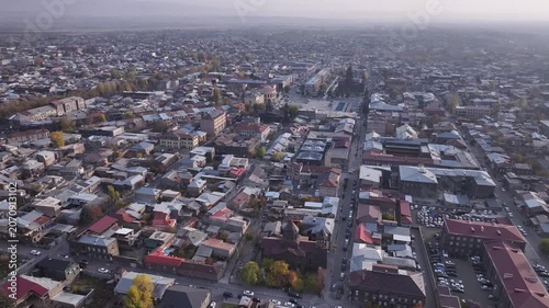 Aerial drone shot of the beautiful city of Gyumri in Armenia, showcasing its historic architecture, busy city squares, streets, and the famous landmark Holy Saviour's Church during autumn.

