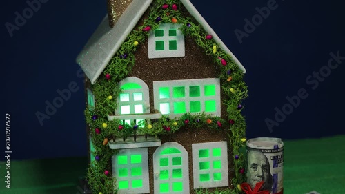 On a dark blue background and green cover is a decorated house with dollar bills nearby