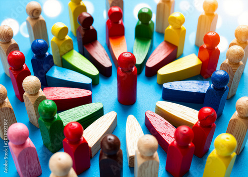 Multi-colored wooden figures arranged in a circle on a blue background symbolize diversity and unity in teamwork