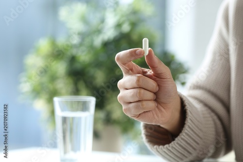 White capsule held by a hand close up pharmaceutical photo