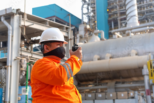 Tableau sur toile Industrial worker in hard hat and mask using walkie-talkie at power plant