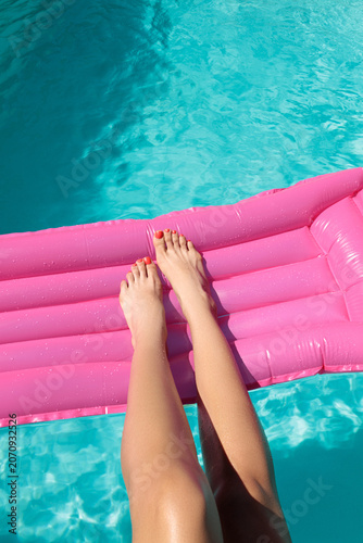 young woman relaxing in the pool, A woman's feet with red pedicures on a pink mattress  in the pool