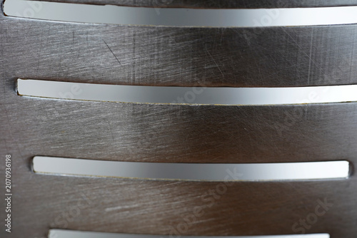 Brushed Stainless Steel Slotted Surface – Industrial Metal Texture Background. Close-up of a brushed stainless steel surface featuring clean horizontal slots and fine metallic grain texture.