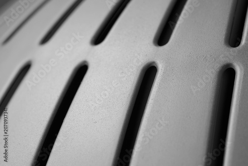 Industrial Metal Texture Background. Close-up of a brushed stainless steel surface featuring elongated ventilation slots arranged in a clean geometric pattern.