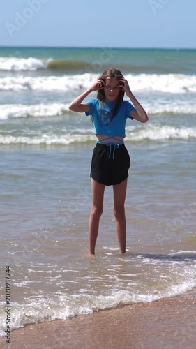 Pretty little girl in a swimsuit, sun glasses and hat relaxing on the beach near sea. Smiling cute little girl on vacation. Adorable girl in a big straw hat looks at the sea. Summer travel concept