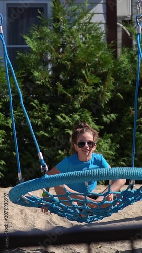 A teenage girl with an electronic key bracelet and sunglasses is relaxing in a hammock.
