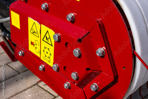 Fotografie Tight detail of a red painted industrial hose reel mounted on a light-colored ti