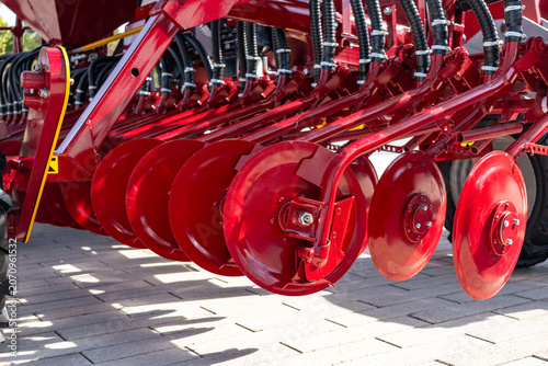 Foto Close-up view of a red disc harrow attachment arranged in a row on a paved surfa