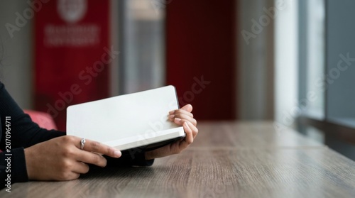 Close up female student hands holding a blank notebook on wooden table for study background and note taking mockup for education layouts