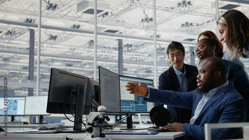 Naklejka premium Multiracial men and women in microchip factory office working together to optimize production, camera A.
