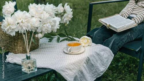 Enjoying a peaceful moment with tea and flowers while reading a book outdoors