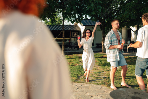 Photos Friends celebrating summer together outdoors, enjoying drinks at a sunny backyar