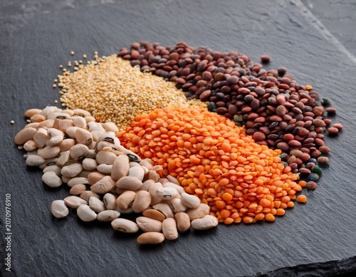 a colorful array of various dried lentils and beans on slate