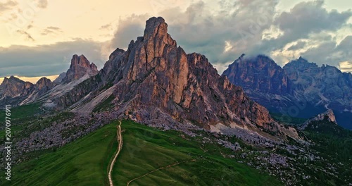 Smooth drone flight around the dramatic rock formations of Passo Giau in the Dolomites. Golden evening light reveals rugged alpine scenery, mountain trails and breathtaking landscapes.