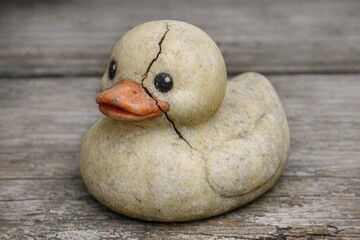 A decorative stone duck perched on a wooden table, suitable for use in home decor or still life photography